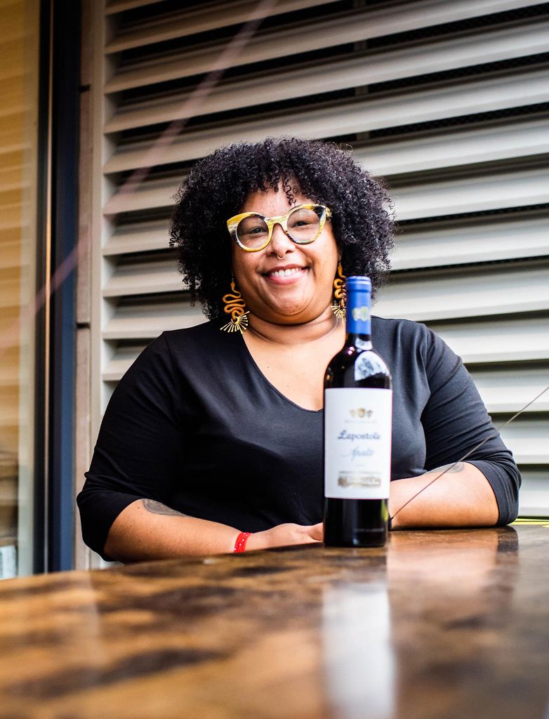 Suhayl Ramirez,a student in the BU Wine Program poses outside of Urban Grape on November 11, 2020. A wine bottle sits in front of him.