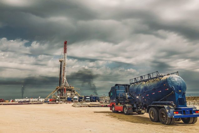 A photo of a truck approaching a fracking rig
