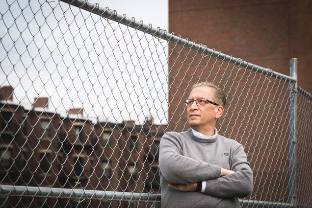 Azer Bestavros, associate provost for computing and data sciences, standing with his arms crossed in a gray sweater and looking off into the middle distance as he leans on a fence near the site of the future data sciences building.