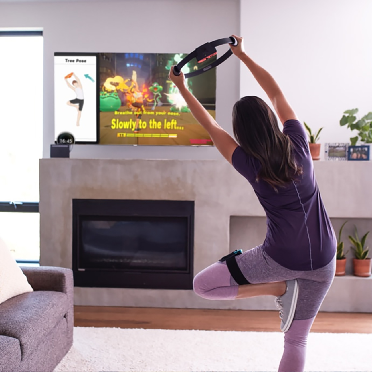 Photo of a woman working out while the Nintendo Switch game Ring Fit Adventure plays on the TV. The TV screen shows an avatar with the ring and words 'Slowly to the left.'