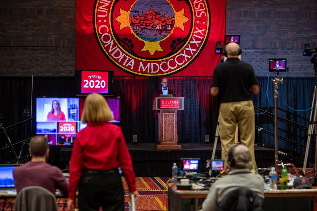 Photo of Dean of Students Kenneth Elmore on a stage as he hosts the 2020 senior breakfast via live broadcast from the GSU Ballroom on May 1, 2020. The photo was taken from behind the production crew, so their equipment is seen in the foreground.
