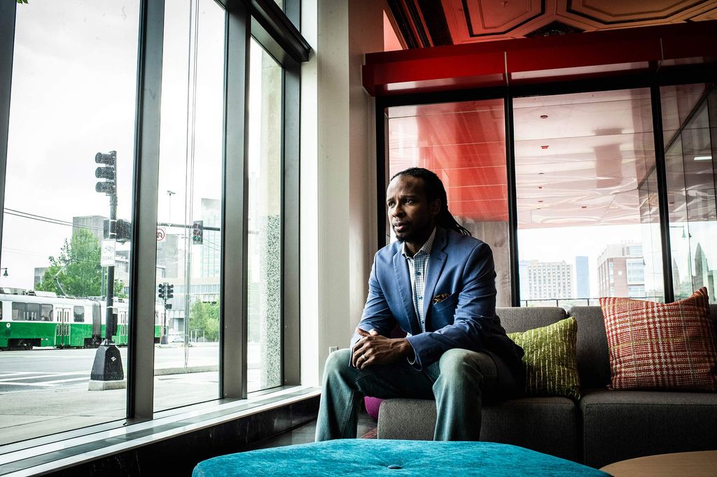 Ibram Kendi photographed at the Howard Thurman Center for Common Good on June 29, shortly after his appointment as founding director of Boston University’s Center for Antiracist Research. He sits on a gray couch and looks out the window.