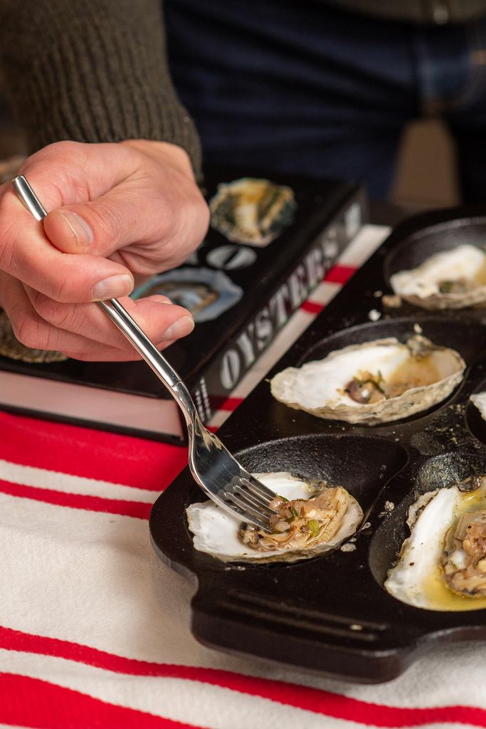 Photo of a fork dressing a tray of oysters. A book called 'oysters' is seen in the background.