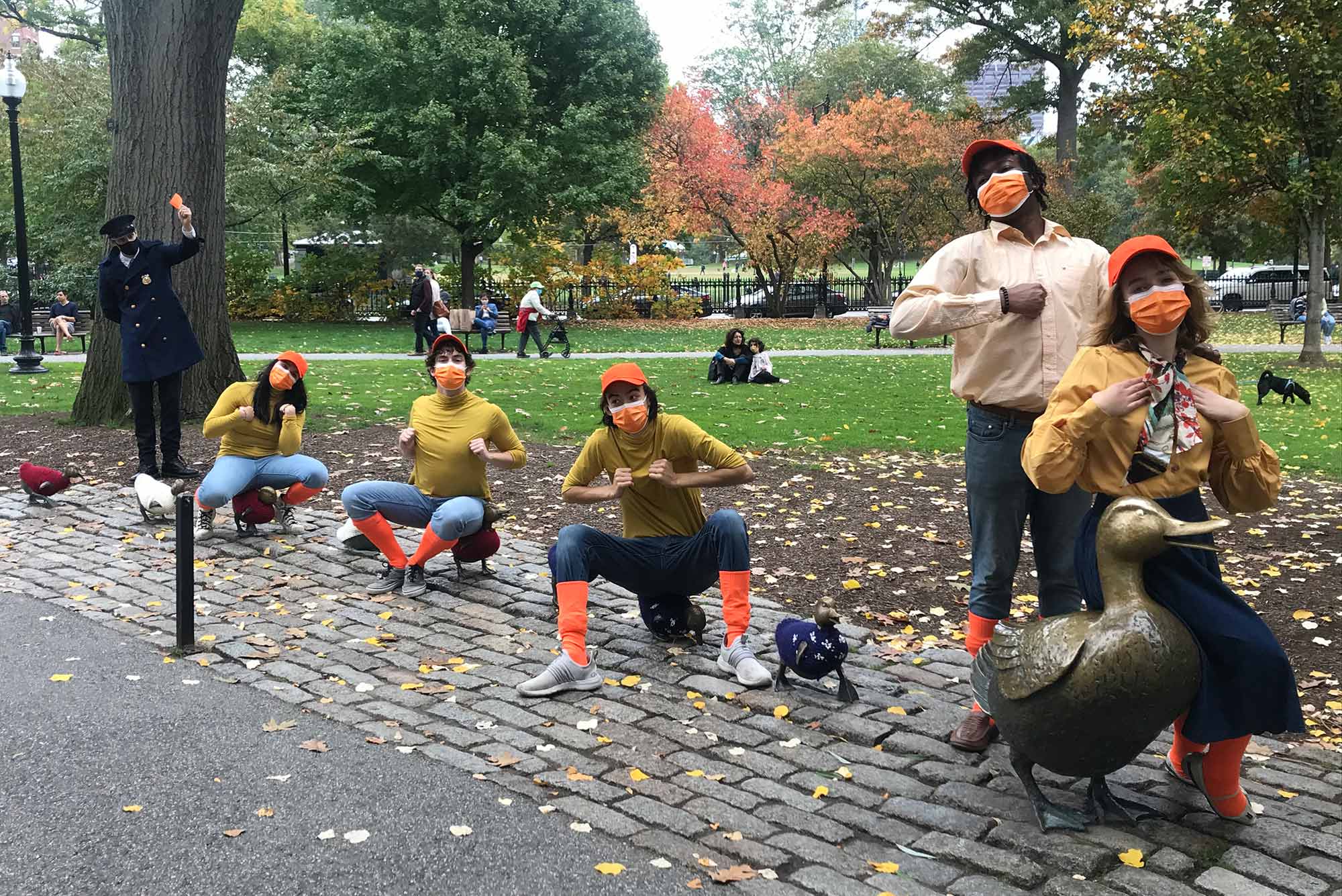 A photo of cast members sitting on the Make Way for Ducklings sculpture in the Boston Public Garden