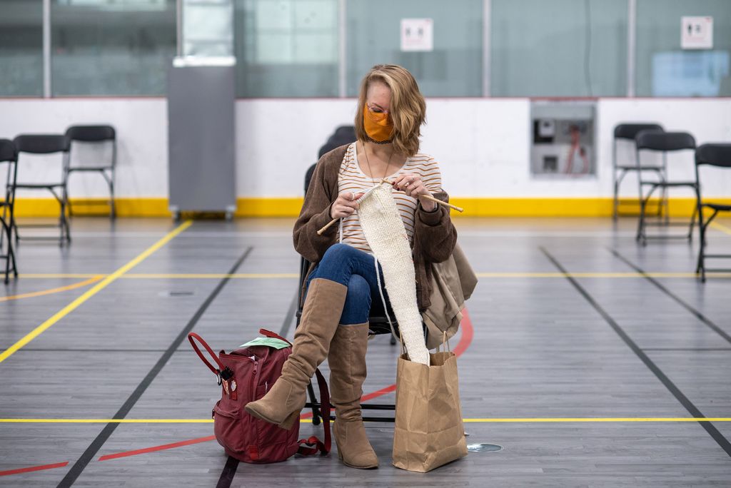 hird-year PhD candidate Ellen Suder, who works with live viruses at NEIDL, passes the time in the recovery area after receiving her first dose of the Moderna COVID-19 vaccine January 15 at FitRec. 