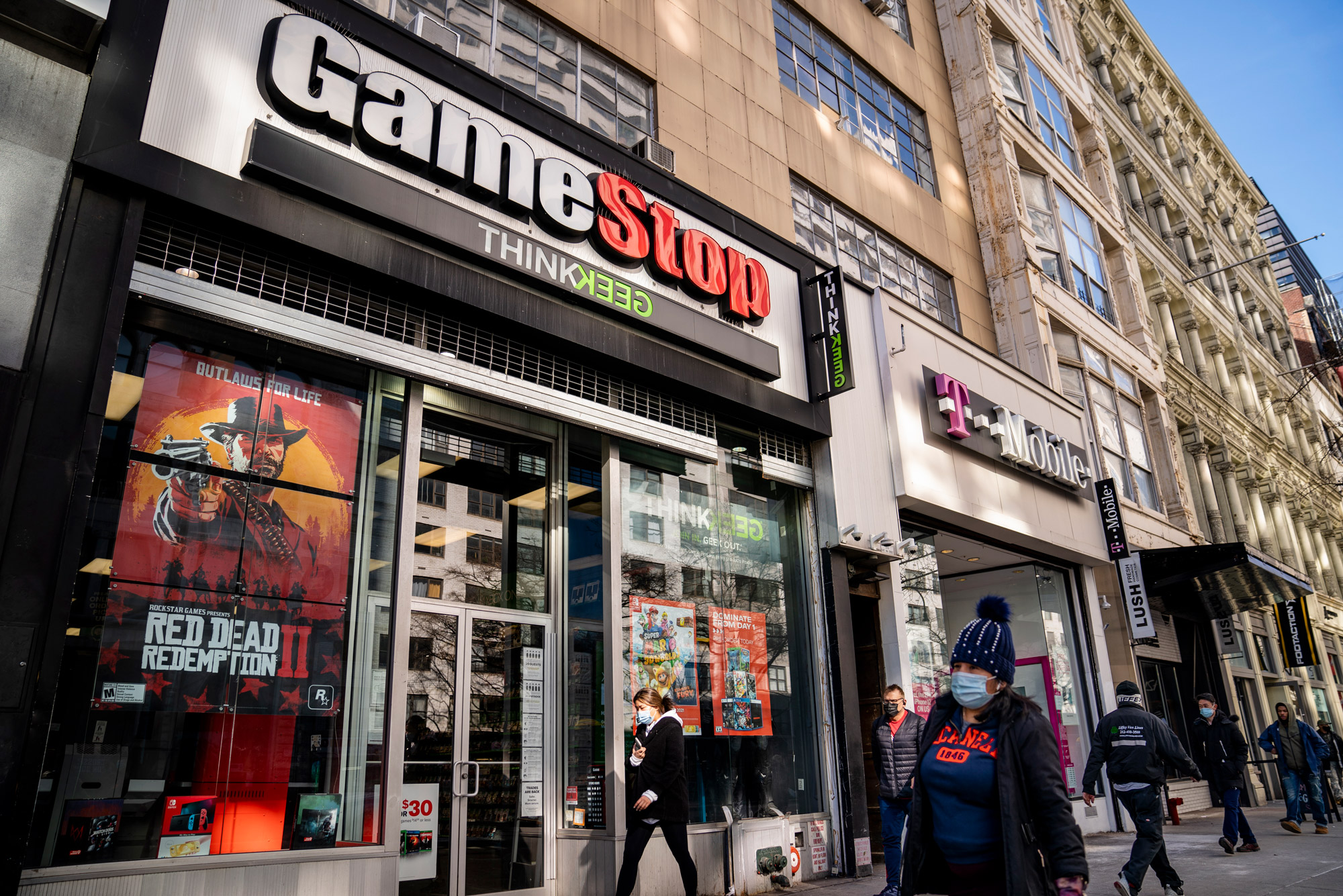 A photo of people walking by a GameStop storefront