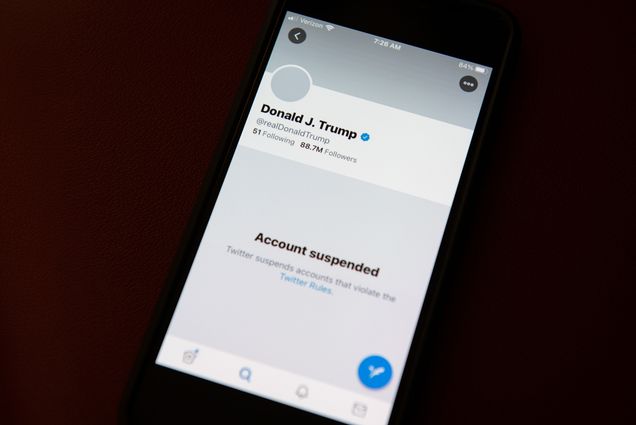 Photo of a cellphone screen on a black background. Donald J. Trump’s recently suspended twitter account is on the screen; his photos are blocked and all you can see is his name, handle (@realdonaldtrump), the number of his followers (88.7million), and the words “Account suspended.”