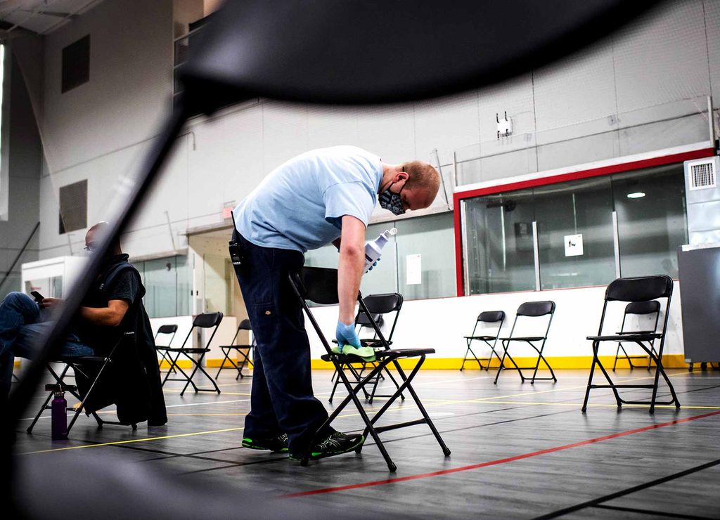 Custodian Joey Pennachio sanitizes chairs in the recovery area at the Boston University Phase 1A COVID-19 vaccine clinic for faculty, staff, and students.