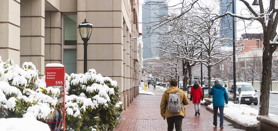 Photo of students walking down Comm Ave with winter attire on. Snowbanks are seen on either side of the sidewalk and snow is seen on the trees. Photo by Jacob Chang-Rascle (COM'22)