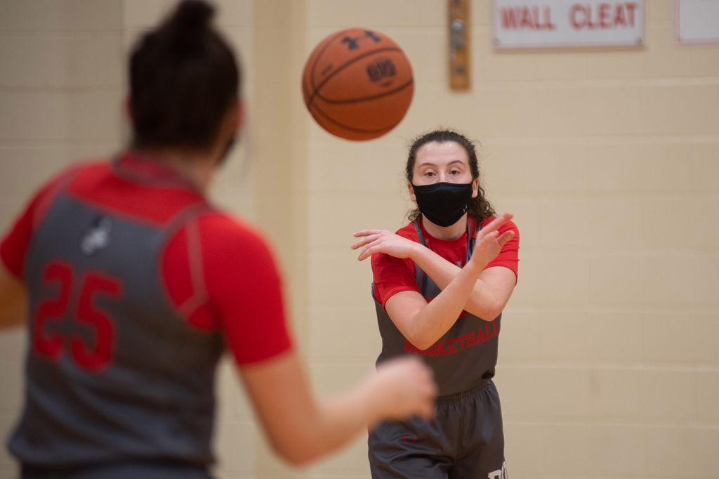 Maggie Pina, a player on BU women's basketball team, passed the ball to a teammate with a number 25 jersey on during a practice in early December during the pre-season. Both women wear masks, and the basketball is seen mid-flight.