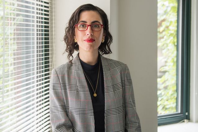 A portrait photo of Sarah Lipson sitting on a window ledge