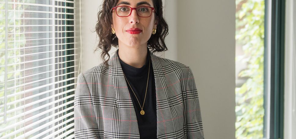 A portrait photo of Sarah Lipson sitting on a window ledge