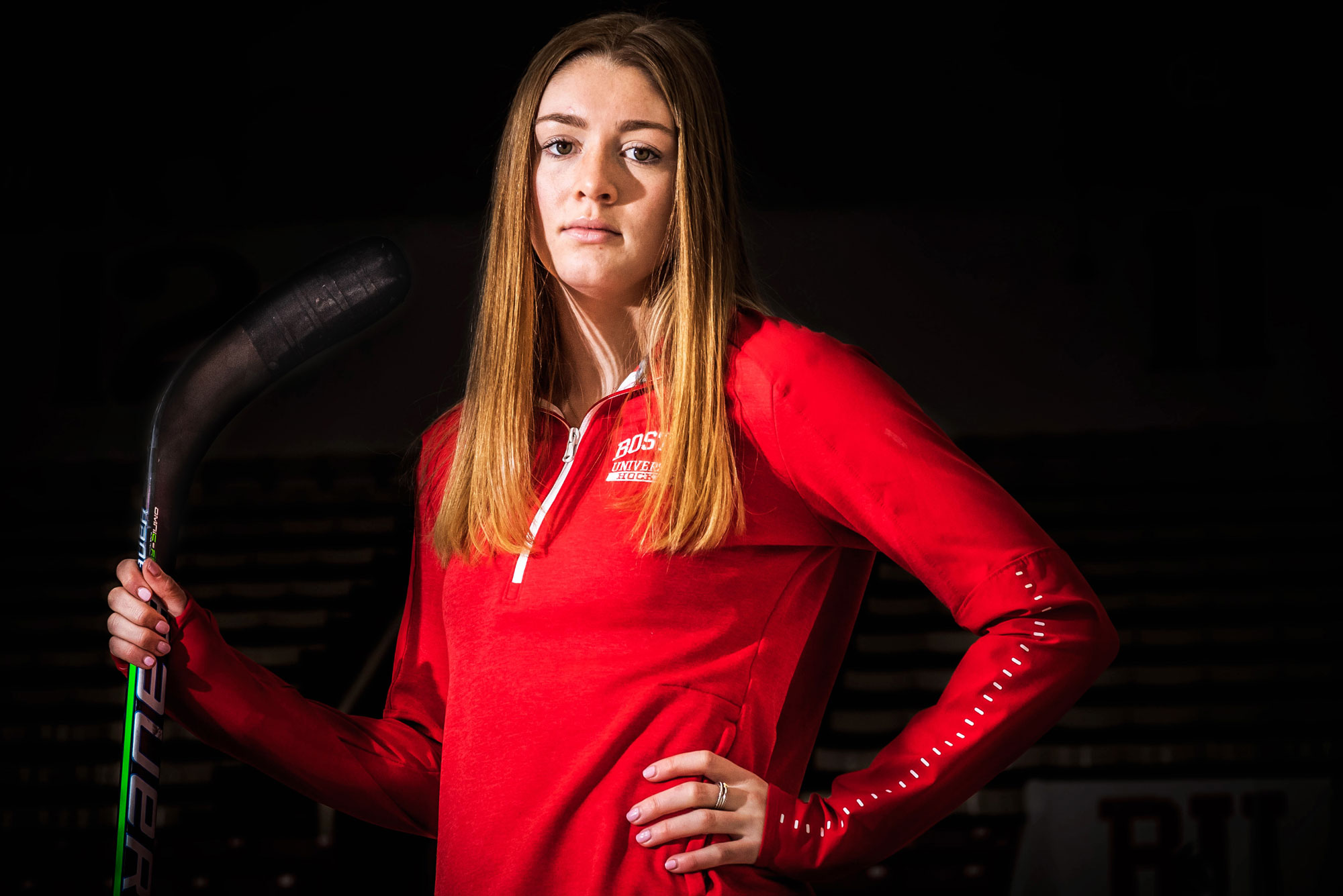 A portrait photo of Jesse Compher holding a hockey stick upright