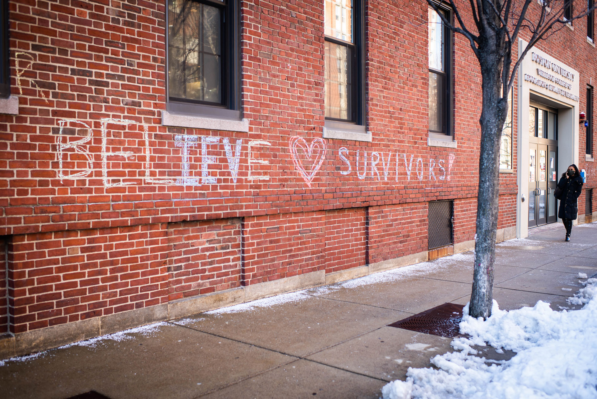 A photo of chalk graffiti on the side of a brick building that reads "Believe Survivors"