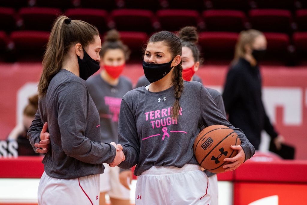 A photo of Katie Nelson and teammate Emily Esposito on the court wearing masks before a game
