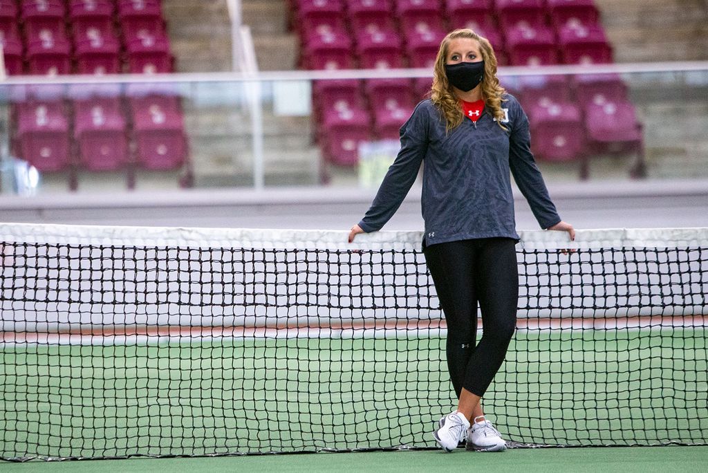 A photo of Kristin Fleagle leaning against a tennis net