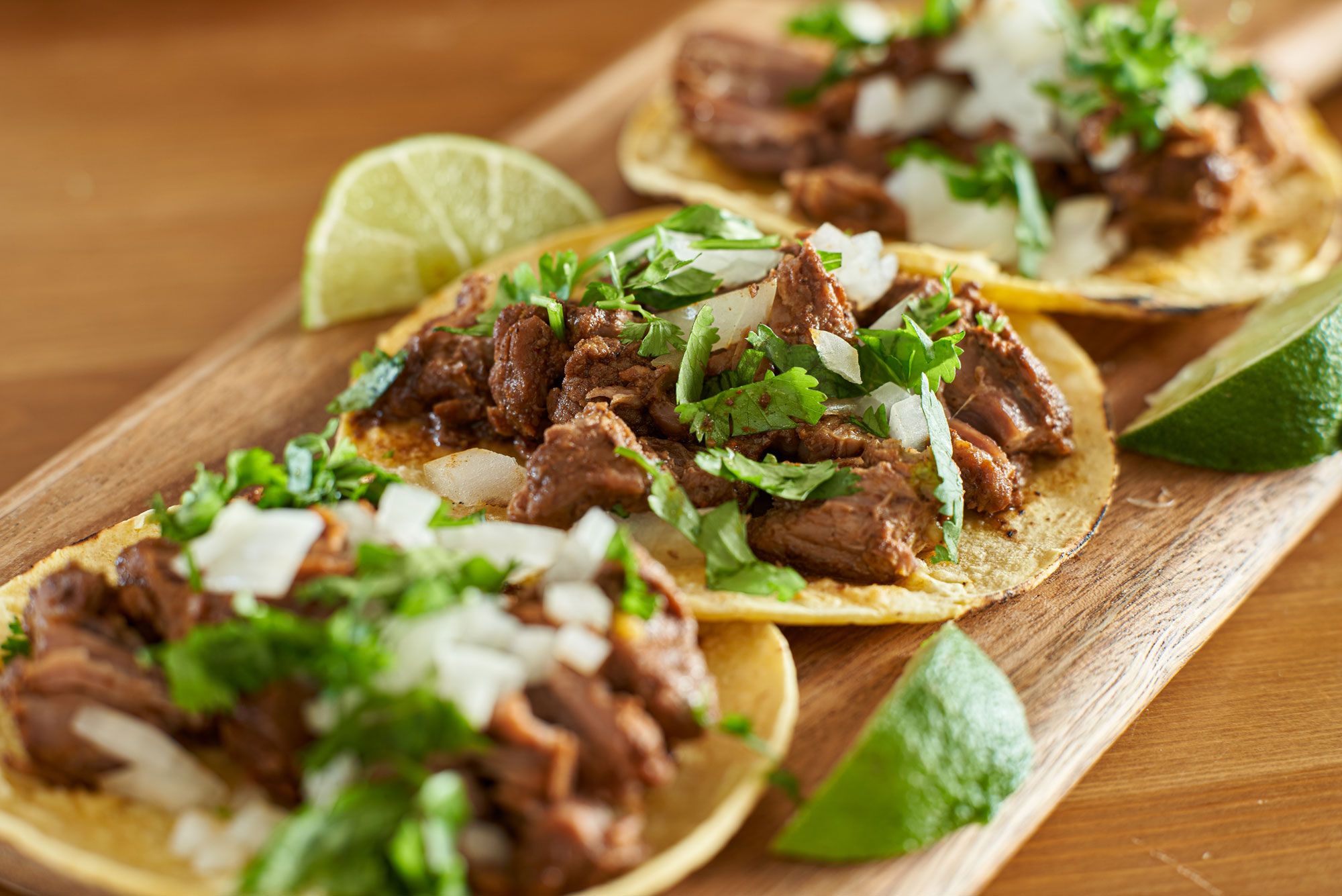 A photo of three tacos with a lime wedge next to them