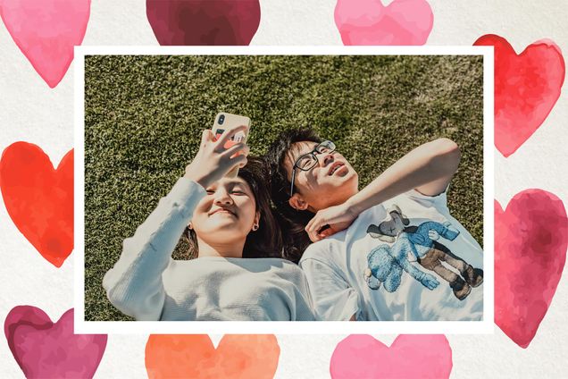 A slightly over-exposed photo of two students laying in the grass together happily looking at their phones. The photo has a white border like that of polaroid, and is on a background with pink, orange, and purple watercolor hearts.