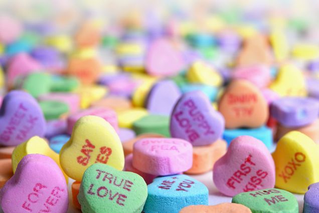 Photo of a pile of colored candy hearts that read phrases like "true love" and "say yes."
