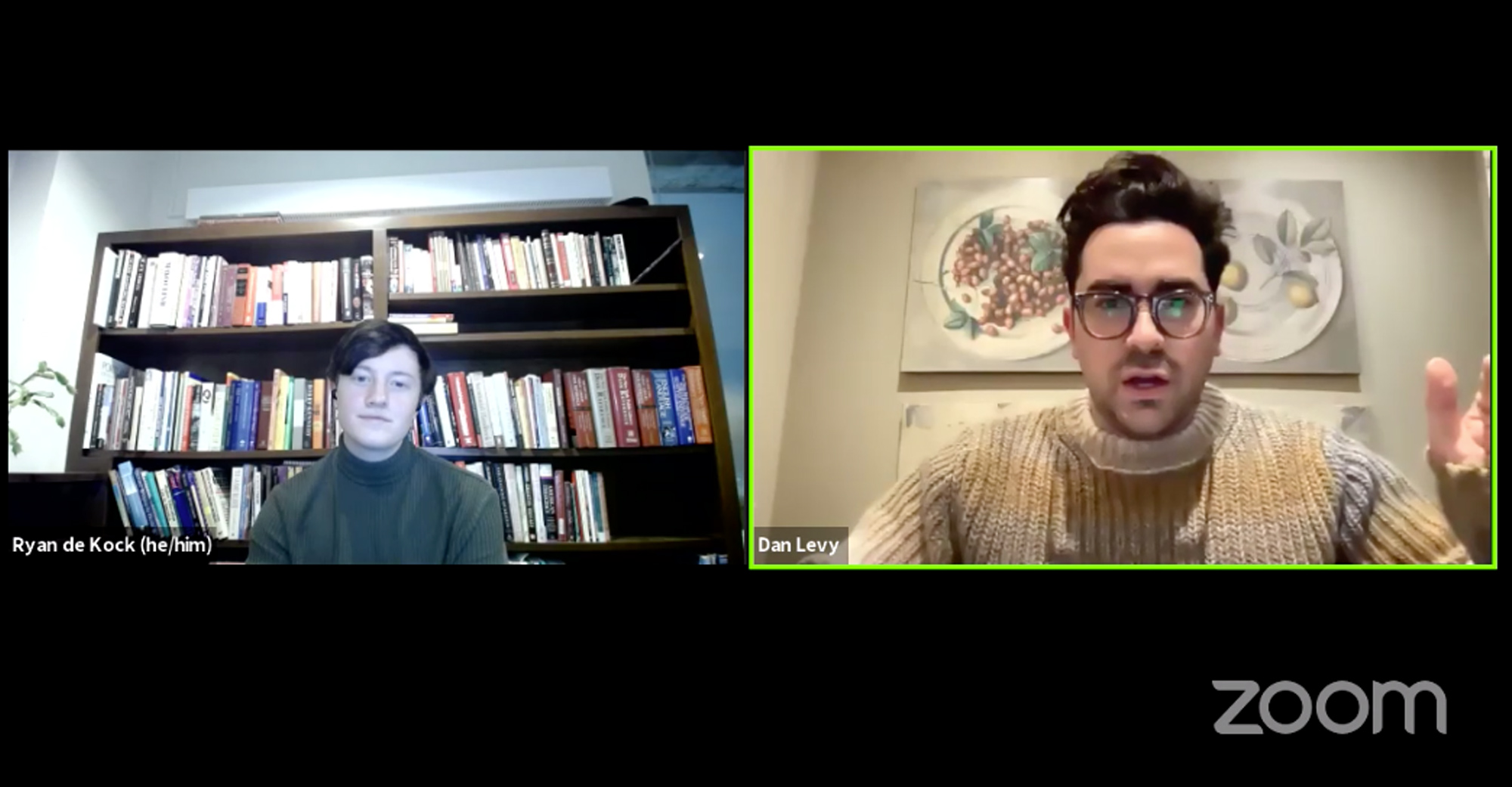 Screenshot of a zoom event on Friday February 19th for BU students. On the panel at left, Ryan de Kock (CAS’22), BU’s Queer Activist Collective’s outreach coordinator, who wears a greenish turtle neck and smiles slightly as he sits in front of a bookcase, interviews Schitt’s Creek cocreator, showrunner, and star Dan Levy, who was his hand raised mid sentence, and wears large glasses and a thick grayish tan sweater.
