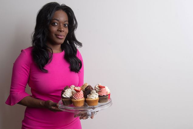 A photo of Shironda White holding a tray of cupcakes.