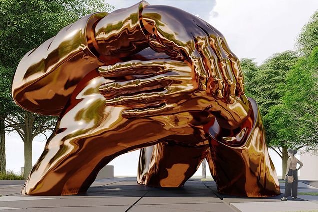 A photo of The Embrace sculpture. The sculpture depicts a group of golden hands joining together.