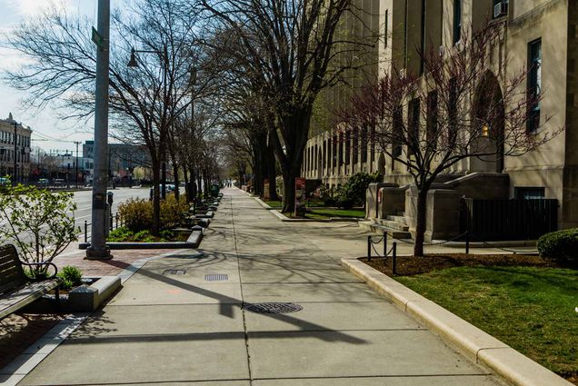 Drone photos of a near-empty campus at the beginning of the 2020 Covid-19 pandemic. A sidewalk along Comm Ave, with CAS buildings on the right, is empty.