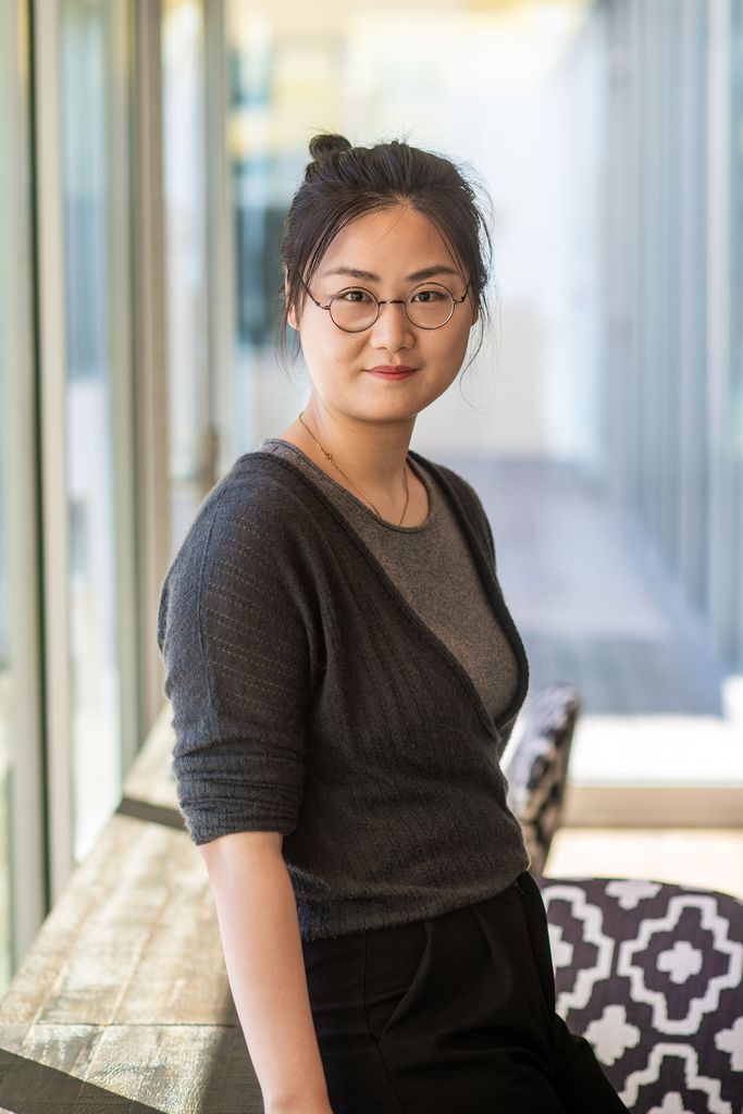 Photo of Chen Ling (ENG’24), a PhD student of Stringhini’s, leaning against a wooden rail, and slightly smiling and looking determined. She wears a gray sweater.