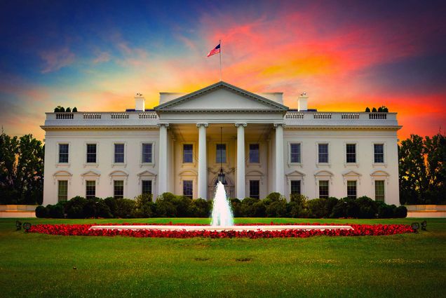 Photo of the White House with a sunset behind it.