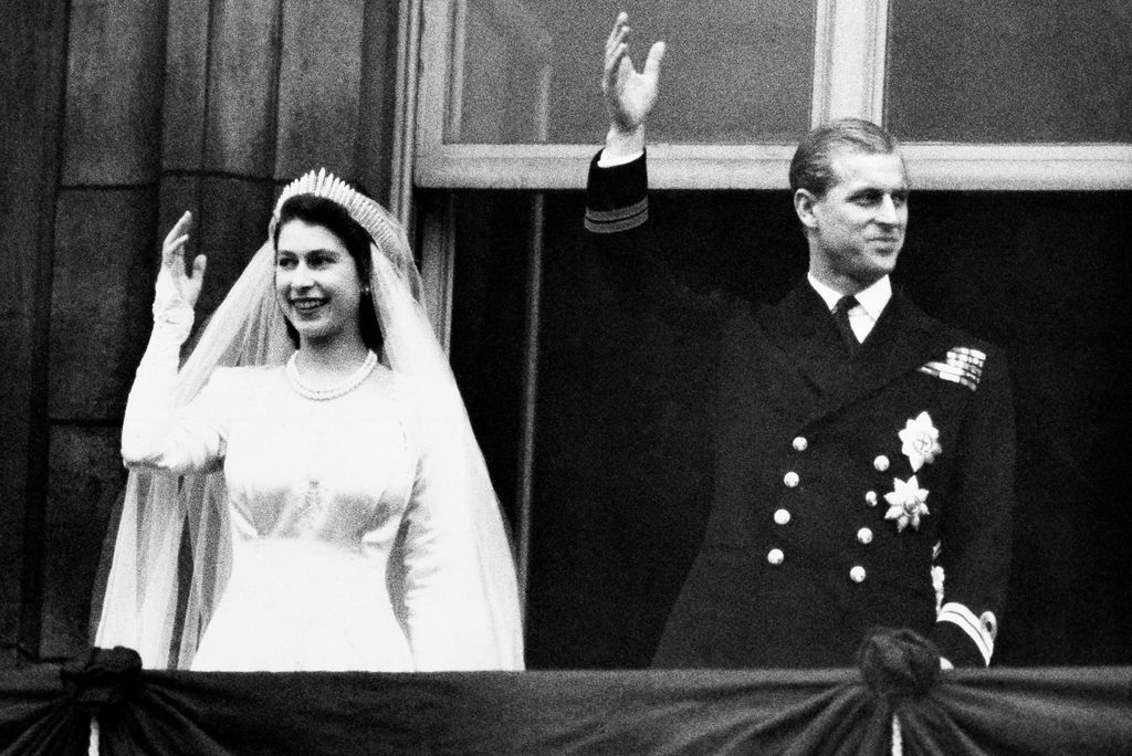 A photo of Prince Philip and Queen Elizabeth on their wedding day. They are waving from a balcony.