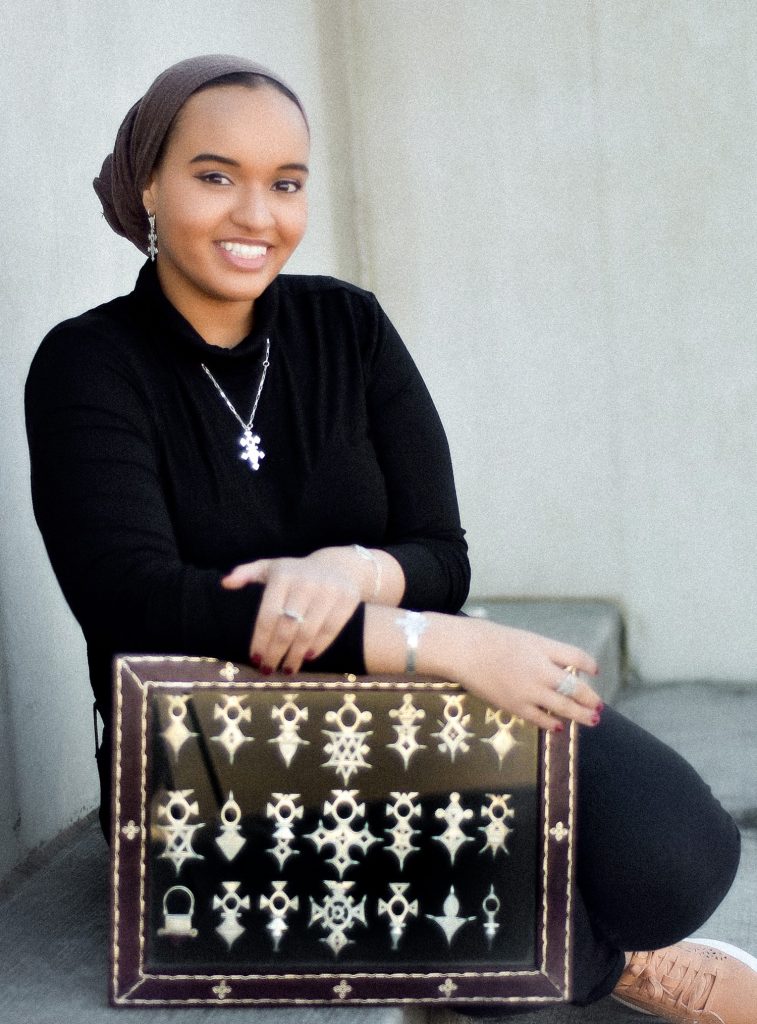 A photo of Malika Kounkourou holding a box of some her jewelry