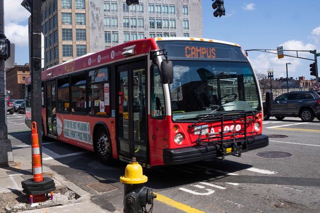 Photo of the BU shuttle bus making a stop at Hynes SB on Mass Ave. on Wednesday, April 21, 2021. The bus’ display sign reads “campus” and the bus is wrapped int he F*ck It Won’t Cut It red advertising campaign.