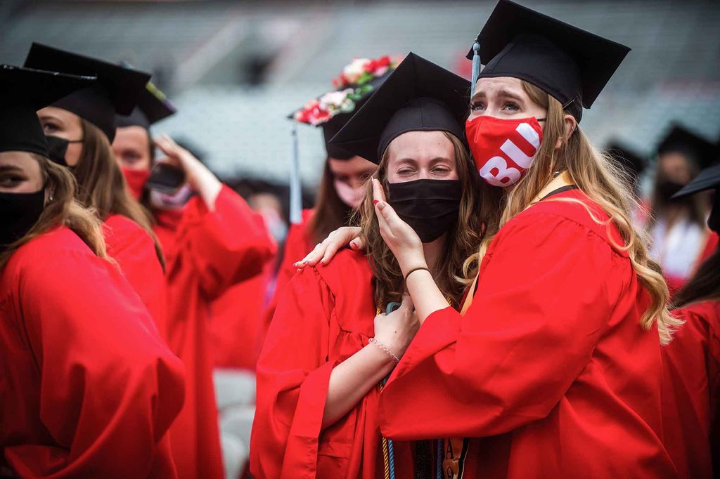 2 emotional graduates cry and hug following Commencement.