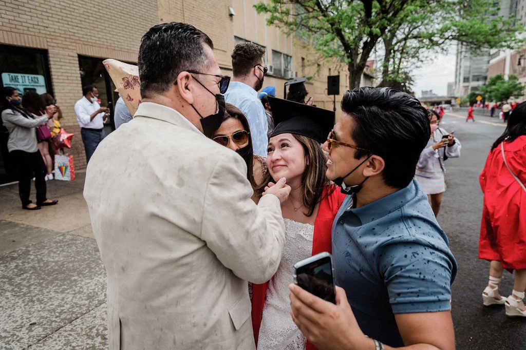 A graduate is greeted and hugged by her family following Commencement.