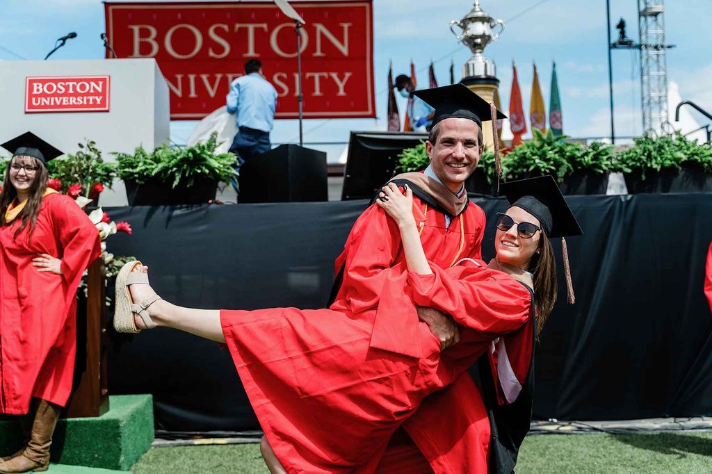 Two graduating students pose for a photo. The man is dipping the woman as if dancing.