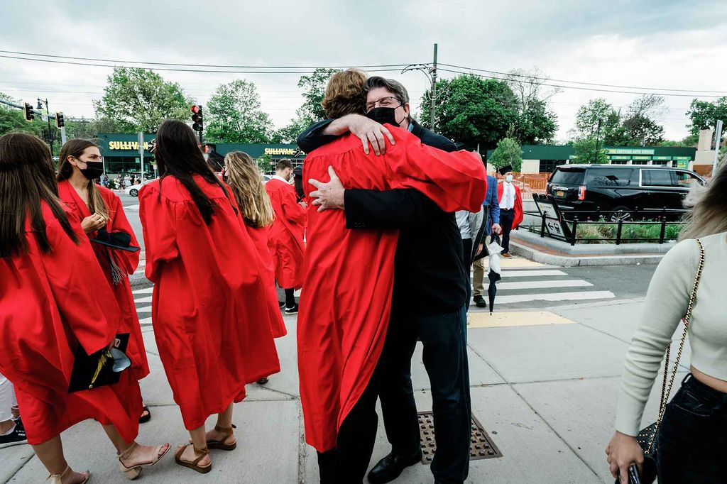 A graduating student hugs a family member on Commonwealth Ave. outside of the BU Commencement ceremony.