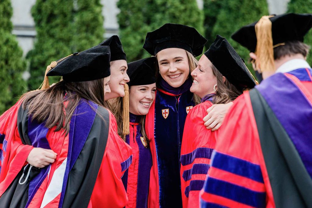 A group of graduate students smile and pose for a photo during the advanced degree ceremony at BU's 2021 Commencement.