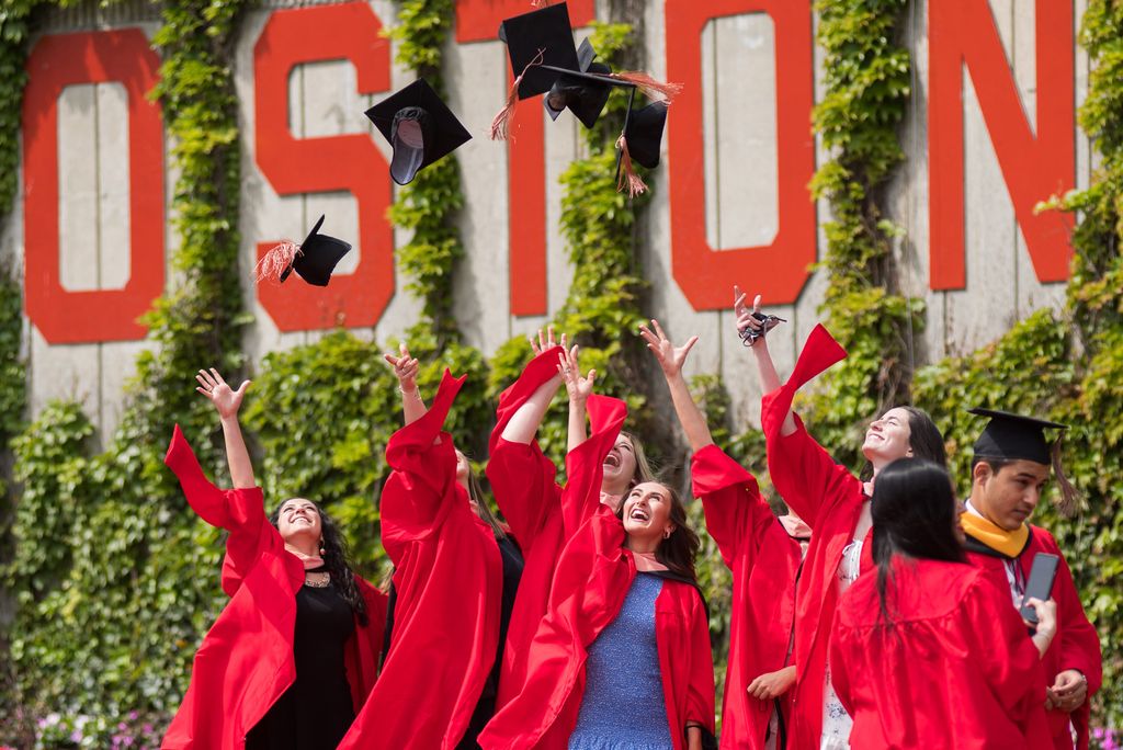 Students celebrate on Nickerson Field after commencement by throwing their caps in the air