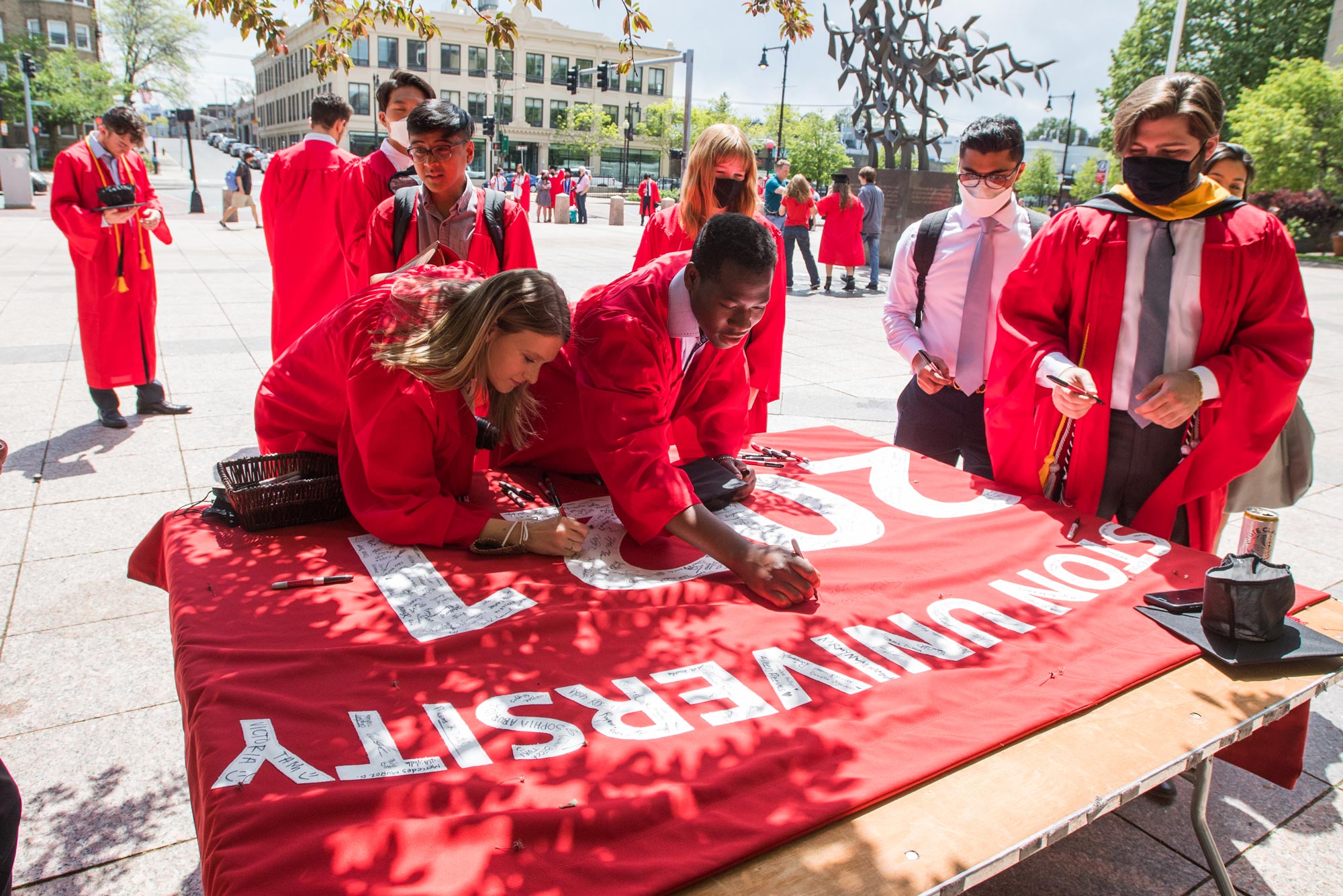 Ryan Gildersleeve (CAS’21) left, and Akram Semakula (ENG’21) sign the senior banner on Marsh Plaza