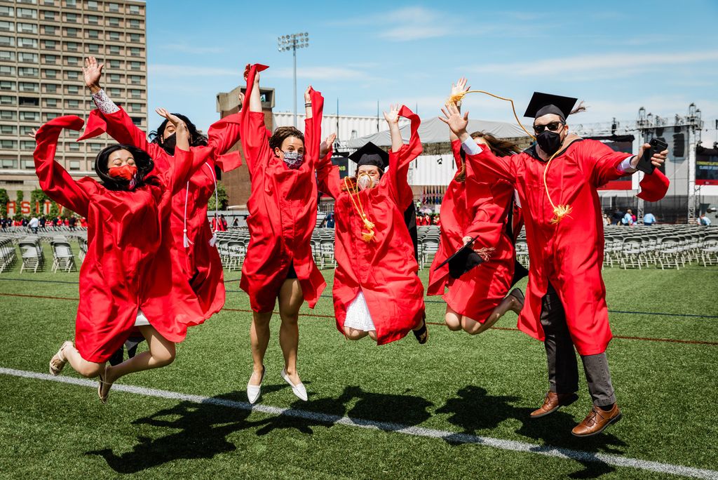 A photo of a group of students in caps and gowns jumping up in the air together