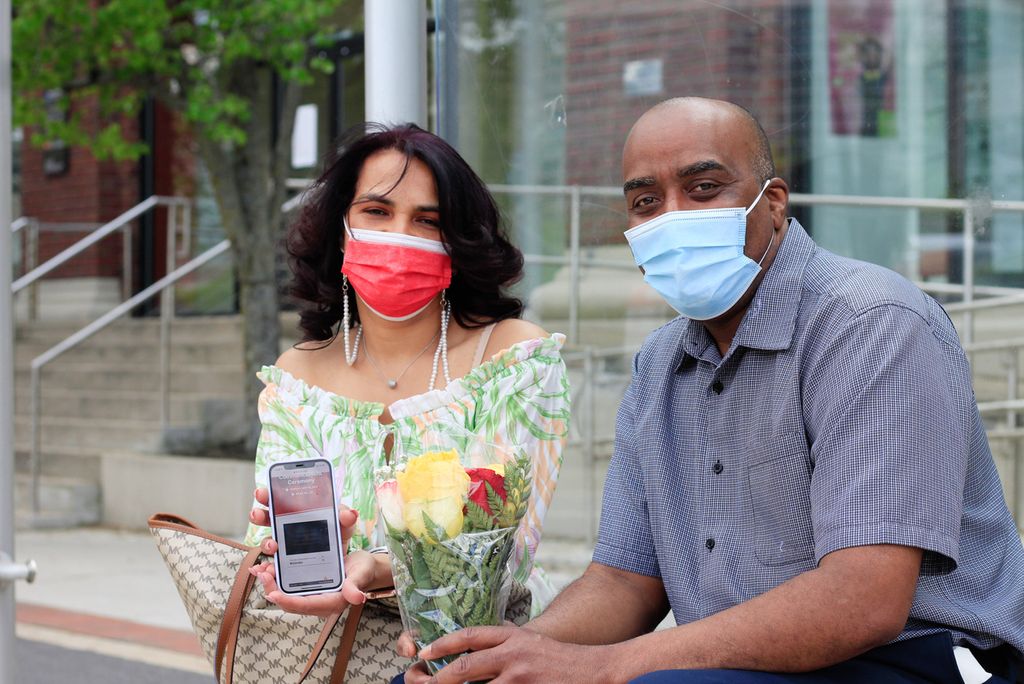 Alberto and Johanny, parents of Danielly Rodriguez watching a livestream of commencement from a Comm Ave bus shelter