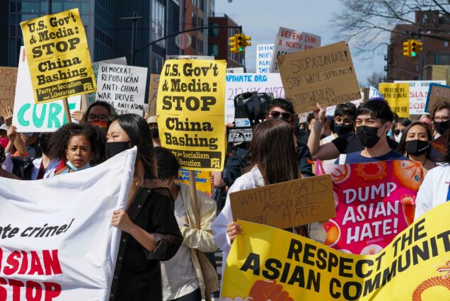 Photo of protestors holding signs during an AAPI Rally Against Hate in Flushing, Queens on March 27,2021. The group of young people, most of them masked, hold signs that say “US Govt & Media STOP China Bashing, party of socialism and liberation,” “Dump Asian Hate!” “Respect the Asian Community,” “Stop Asian Hate! Stop White Supremacy! Stop Western Imperialism”