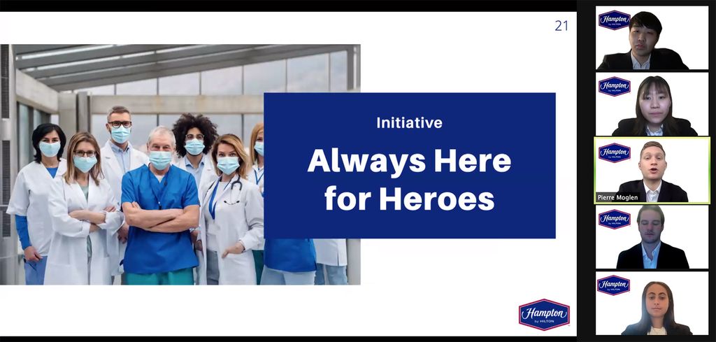 Zoom screenshots of students presenting their marketing plan. The students are seen in formal attire on the right in individual zoom frames, and their slides are seen on the left. The slide has a picture of healthcare workers and reads "Initiative: Always Here for Heroes" 