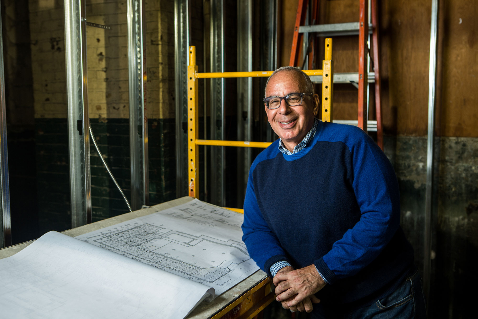 A portrait photo of Gerry Fine next to some blueprints