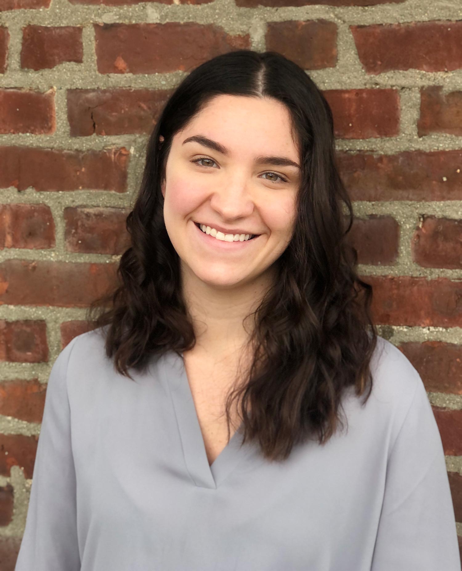 A portrait photo of Alexa Friedman standing against a brick wall