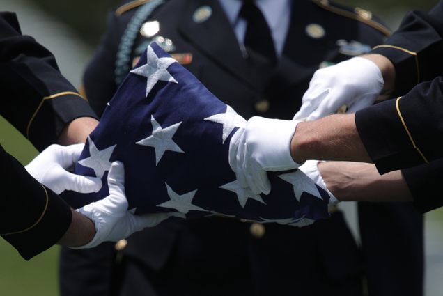 Photo taken in in Arlington, Virginia on June 6, 2019, as members of the U.S. Army’s 3rd Infantry Regiment “The Old Guard” fold a flag during the funeral of World War II Army veteran Carl Mann on the 75th anniversary of the D-Day invasion at Arlington National Cemetery. Soldiers in blue uniforms and white gloves fold an American flag together. Overlay reads "POV"