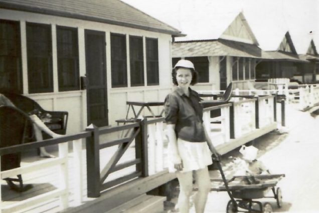 Black and white photo of the author’s grandmother, Marie Moran, in Breezy Point, 1947. She wears a mid-thigh length skirt, hat, and pulls a wagon with a child in it.