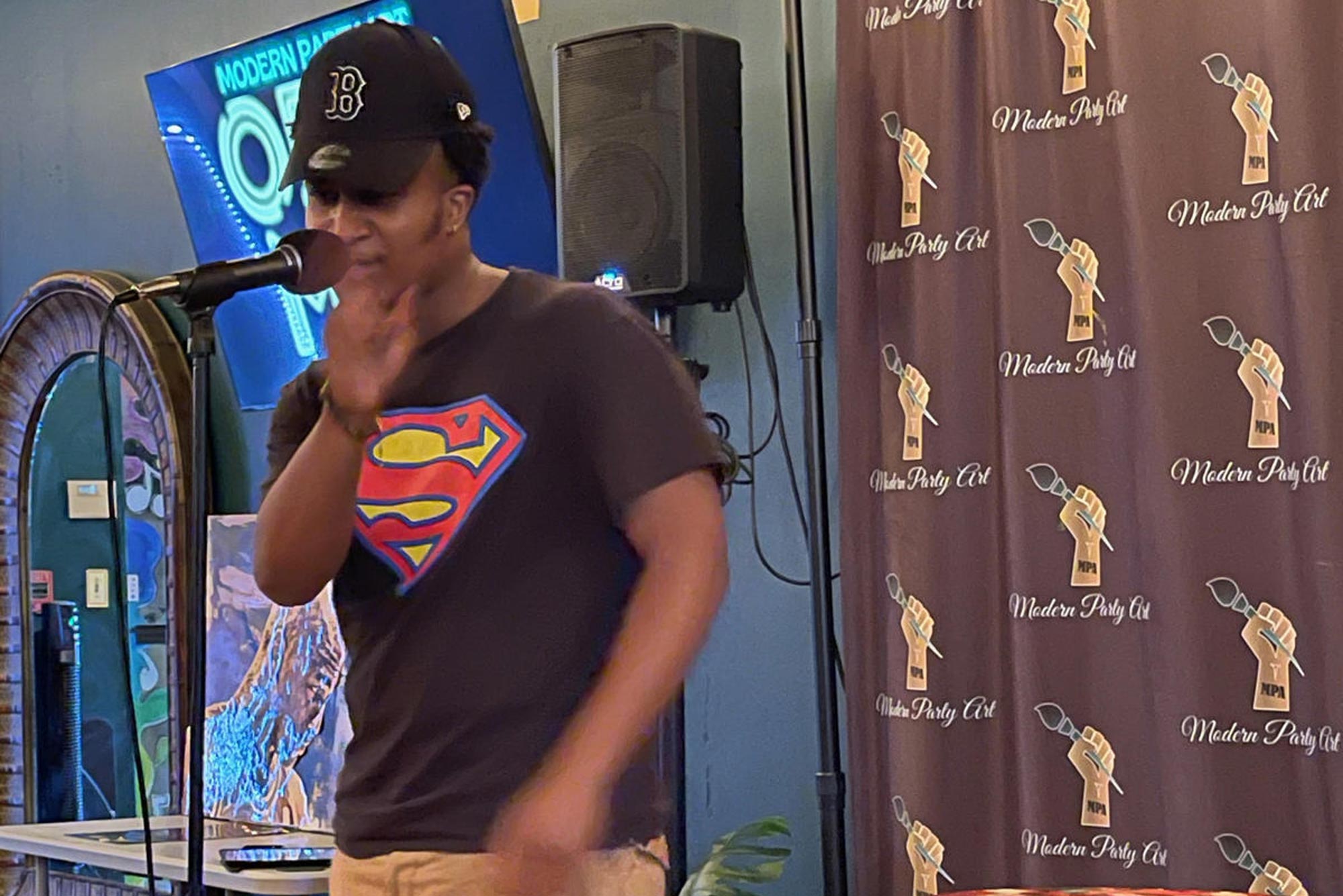 A photo of a performer at a Modern Art Party up on stage for the Open Mic Night.