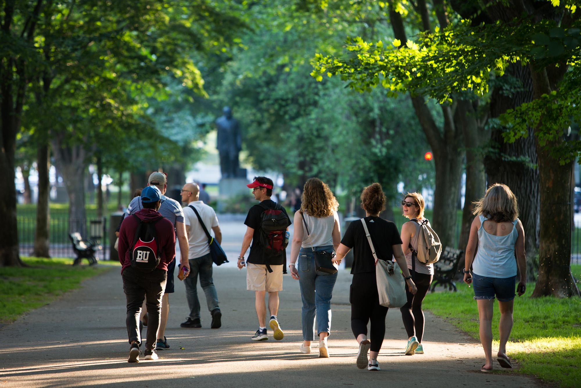 Photo, from behind, of the class walking down Commonwealth Avenue Mall on a bright summer's day.