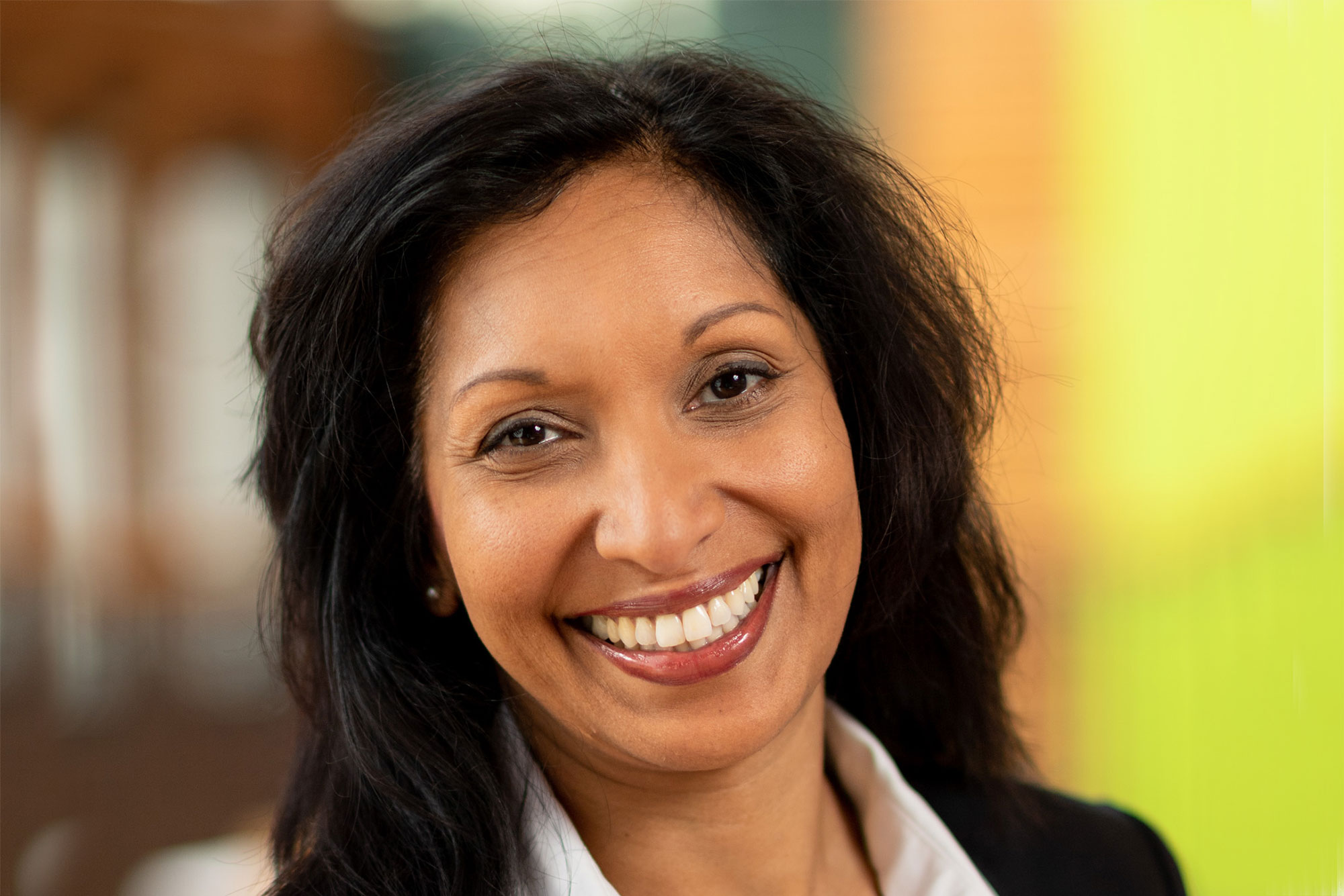 Headshot of Amanda Bailey in a black blazer, smiling. She has dark shoulder length hair.